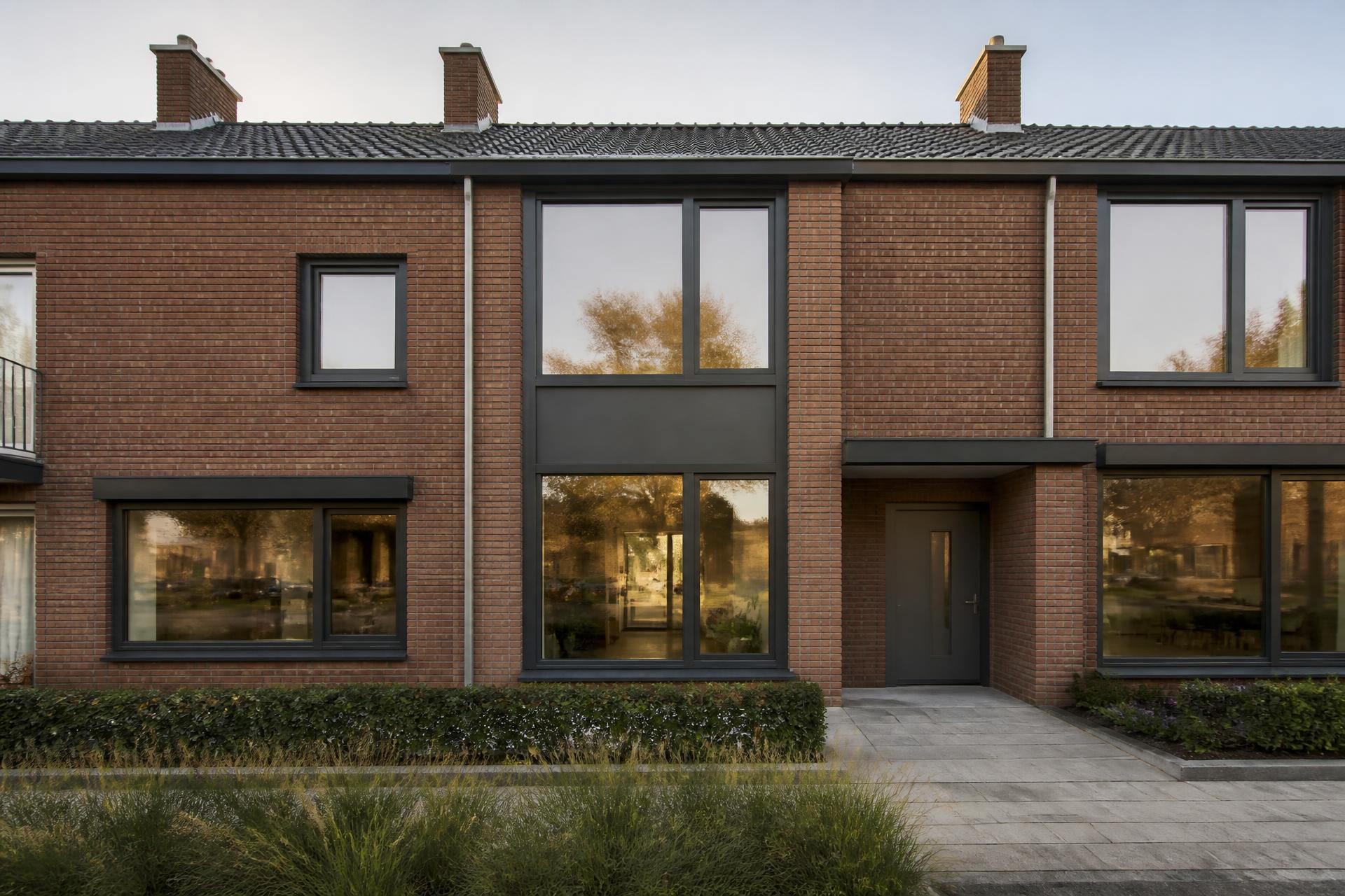 Woning met donkere kunststof kozijnen in een bakstenen gevel